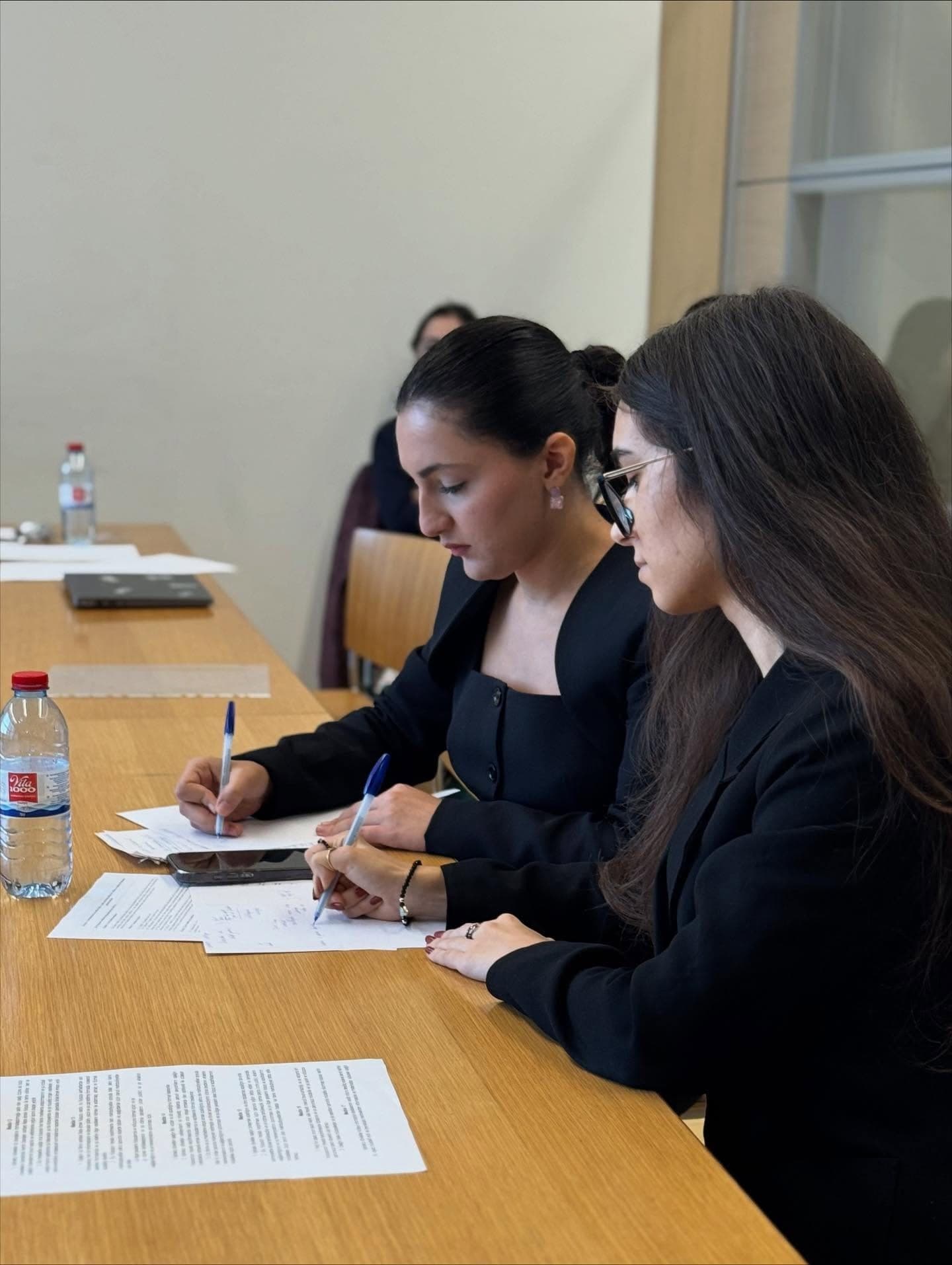 Two debaters leaning over their notes, writing, during a round.