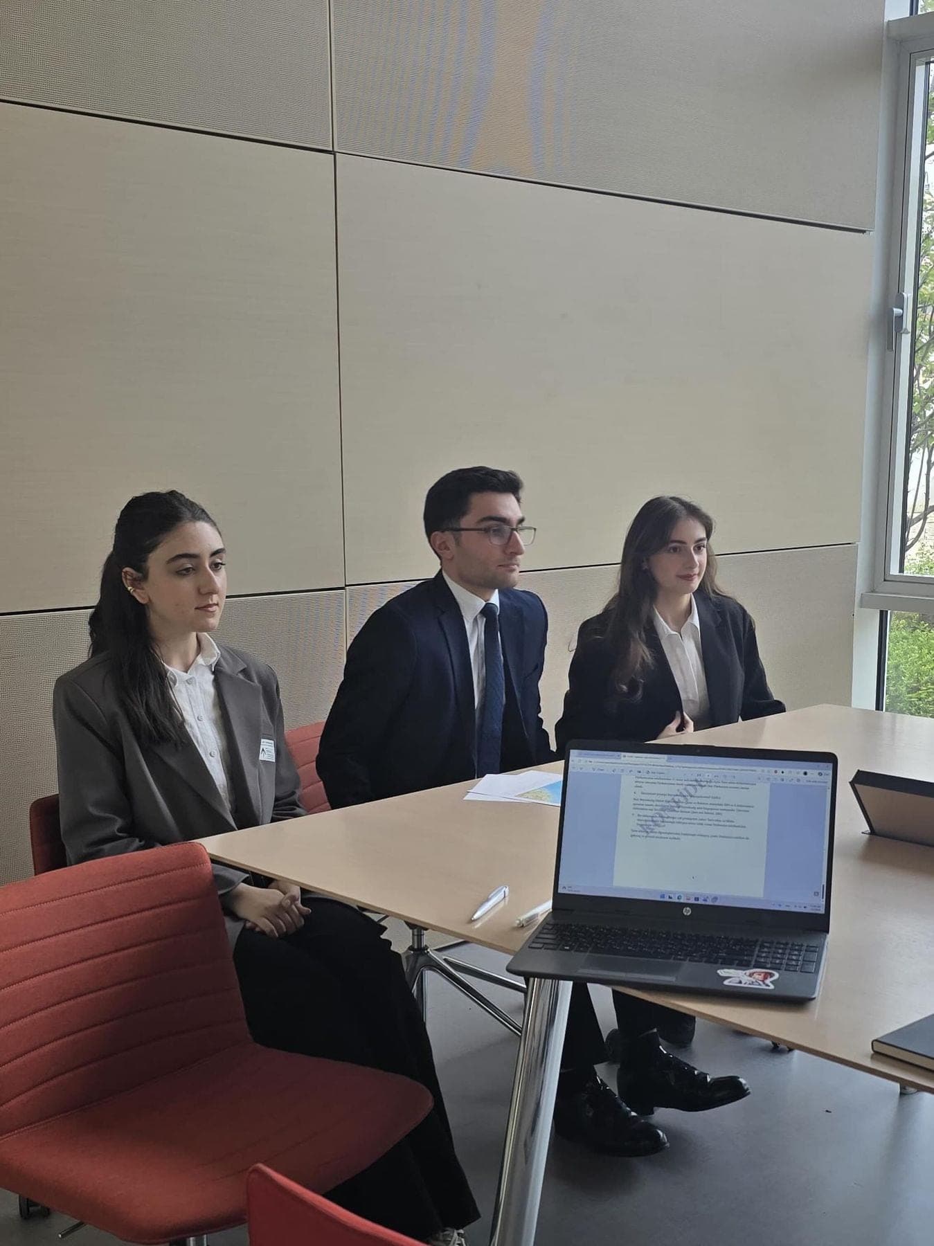 Three moot court participants seated at a table with a laptop.