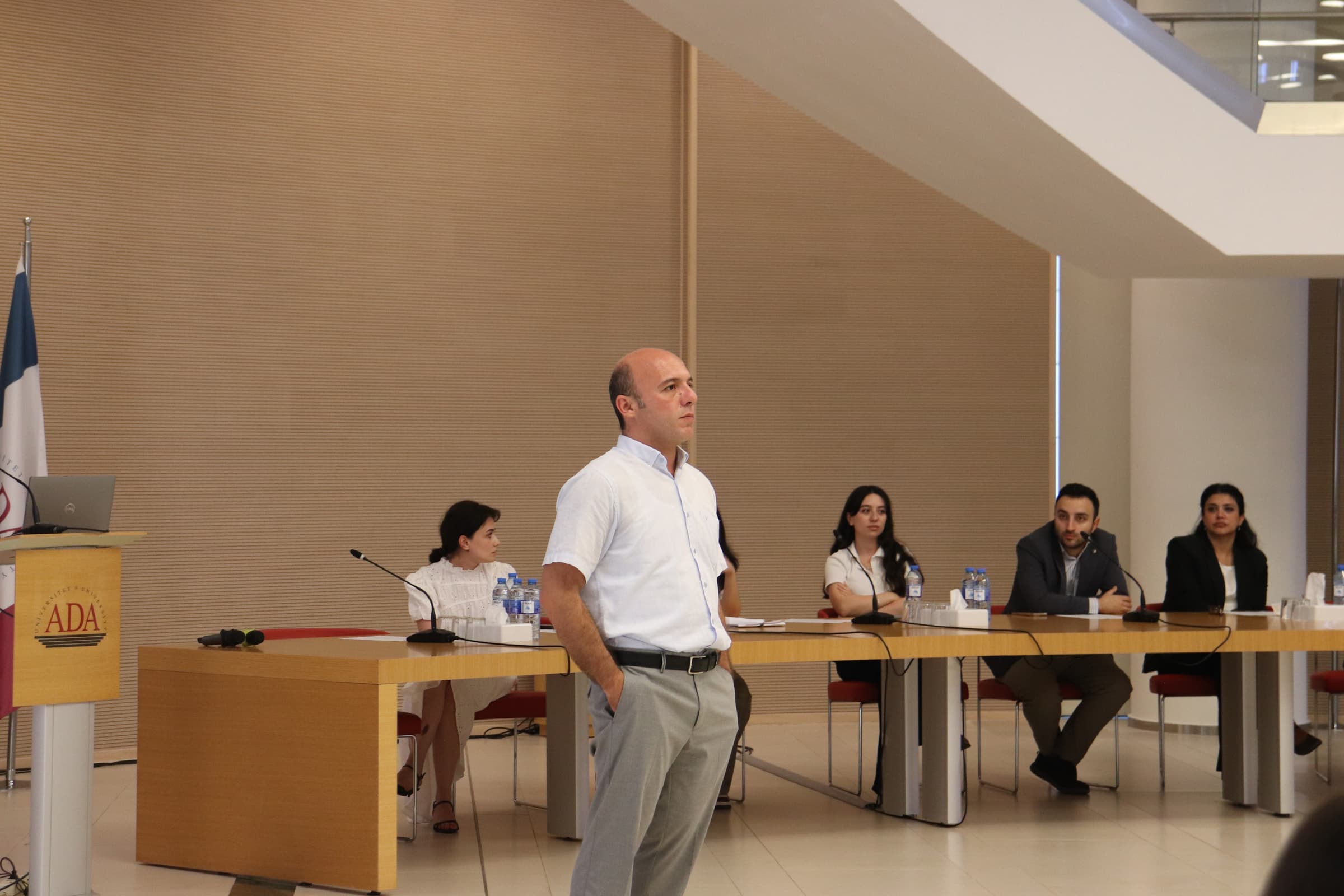 A speaker addresses the hall from in front of the panel table.