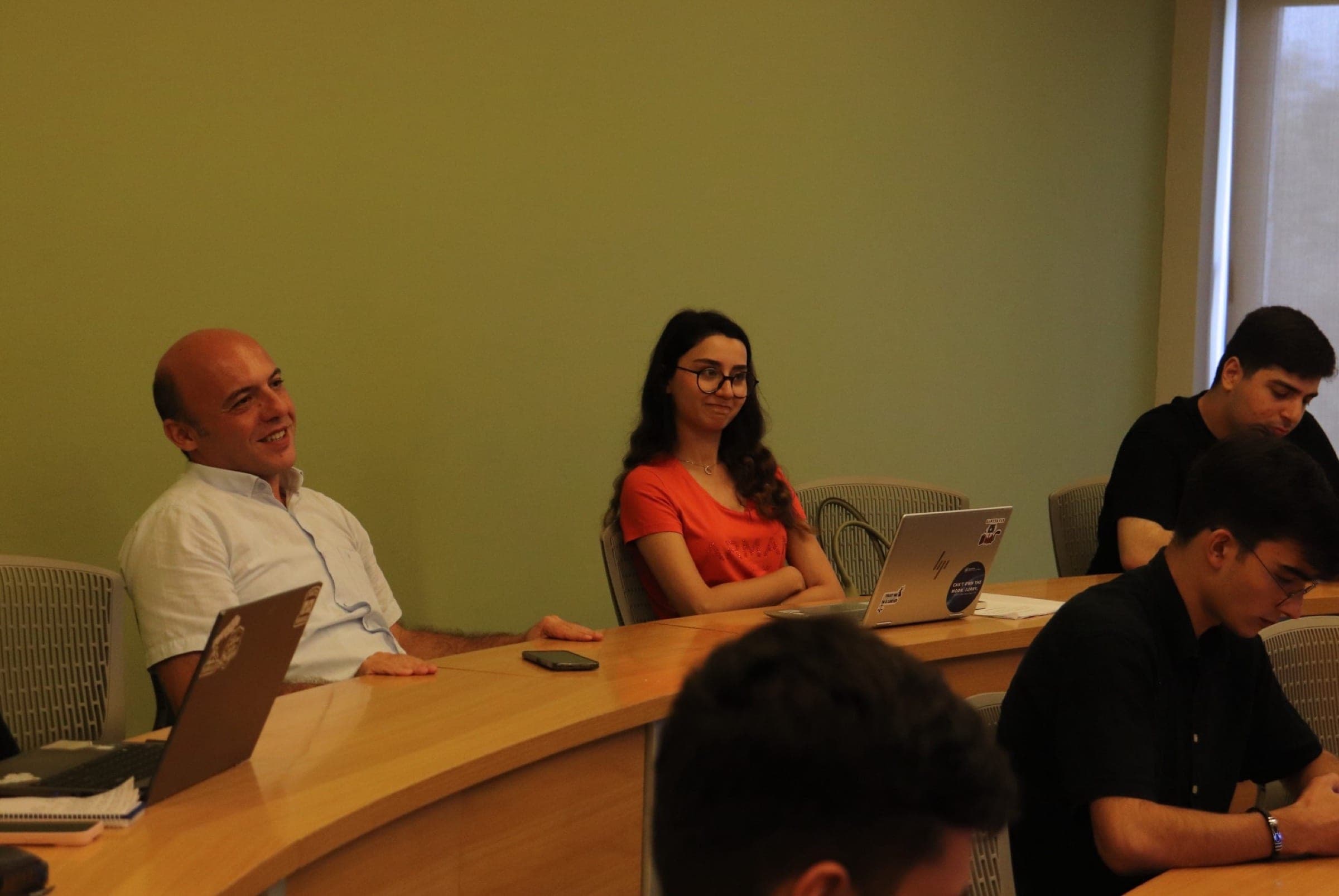 Attendees seated at the seminar desks, laptops open in front of them.