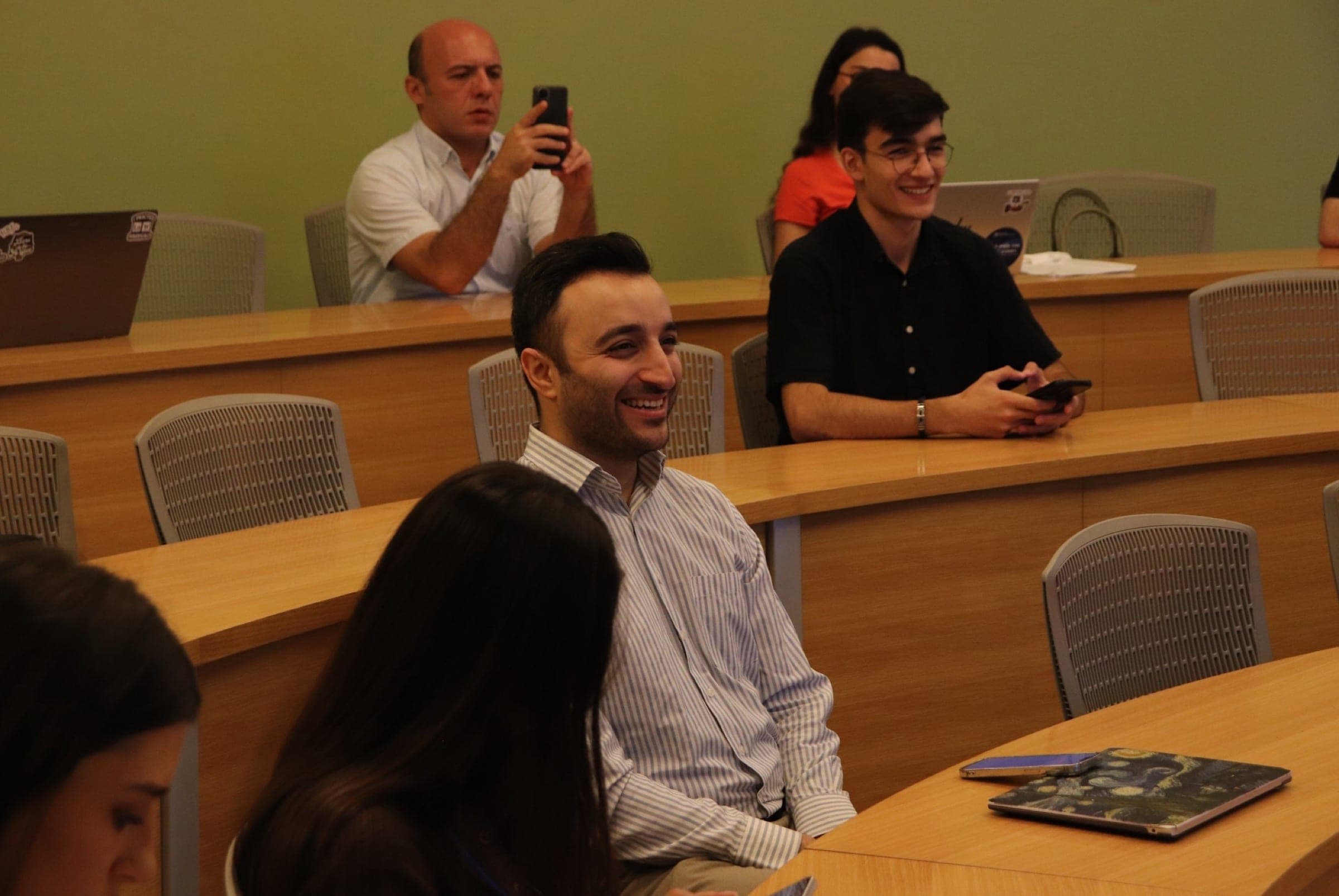Attendees at the seminar during the discussion, one of them photographing the screen.