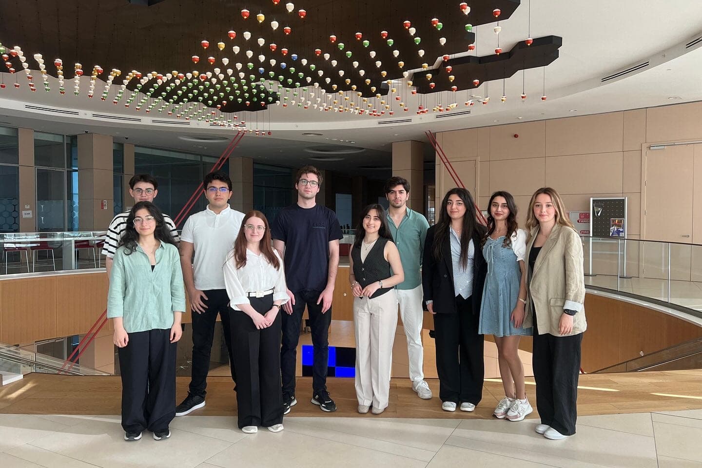 A group of students standing together in a hall with a decorative ceiling.