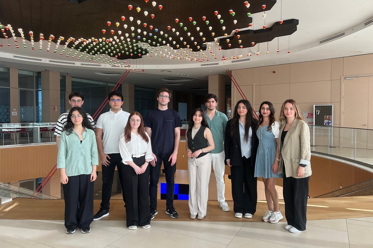 A group of students standing together in a hall with a decorative ceiling.