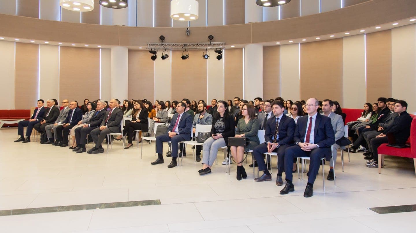 Guests seated in rows in a long, bright conference hall at ADA University.