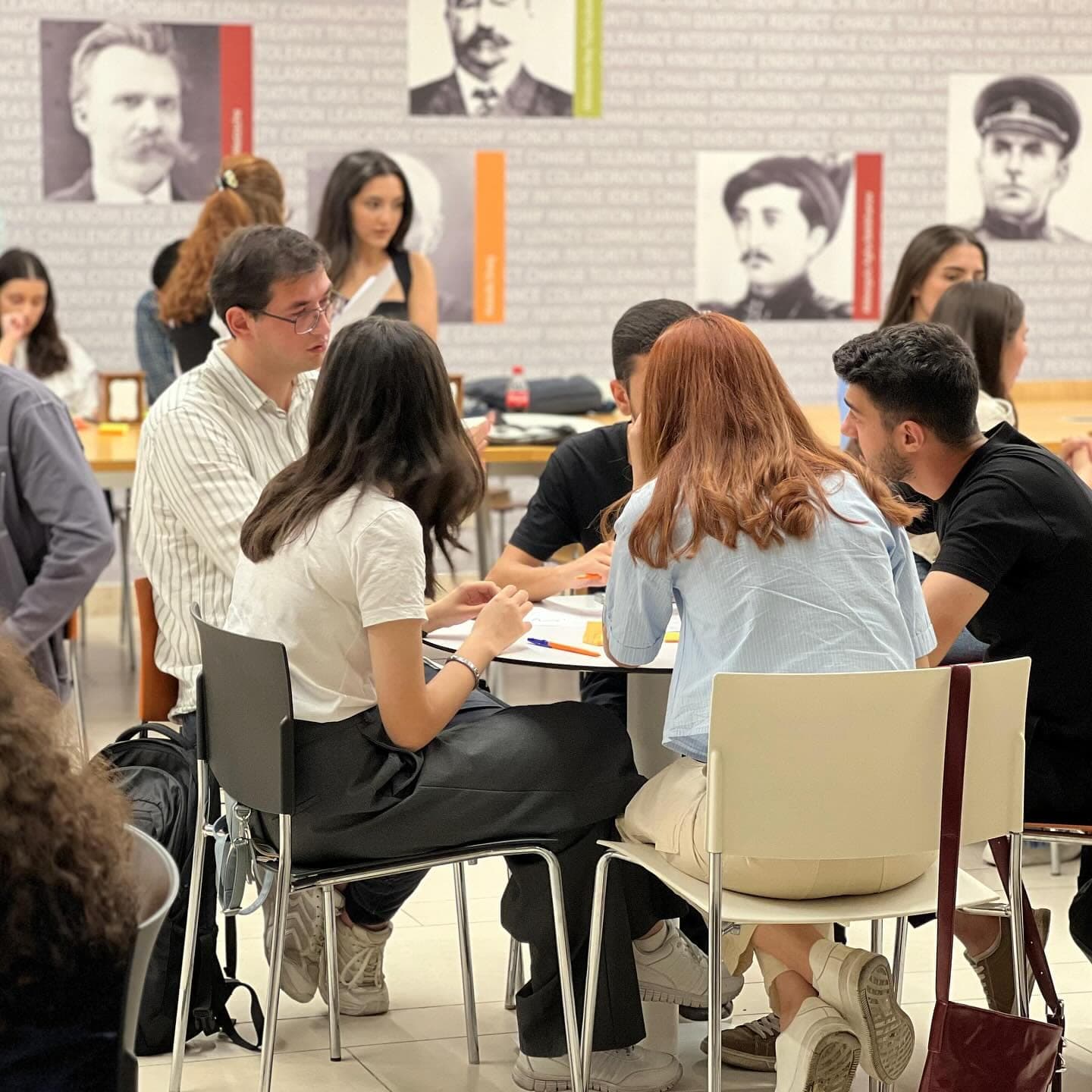 Teams seated around tables, working on their answers.