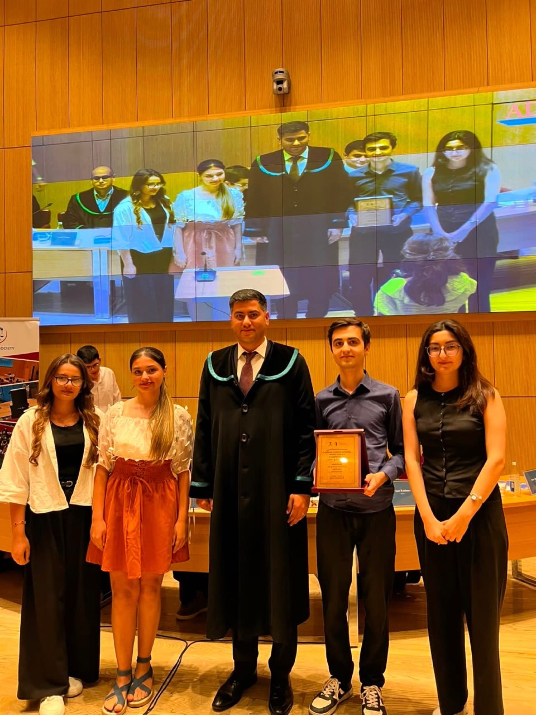 Participants standing with a judge in robes during the presentation of awards.